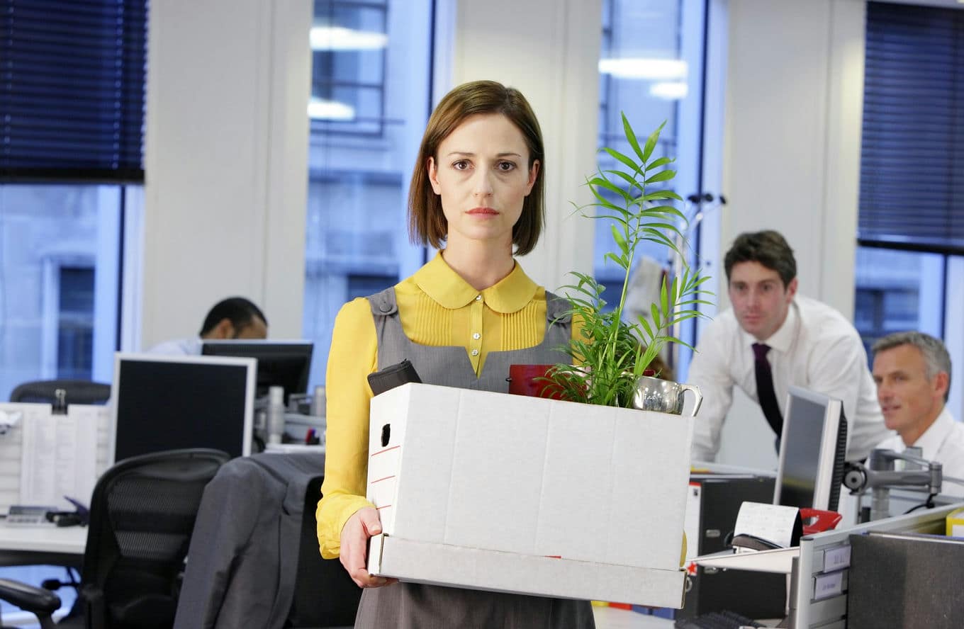 kobieta stoi w biurze z pudełkiem z rzeczami